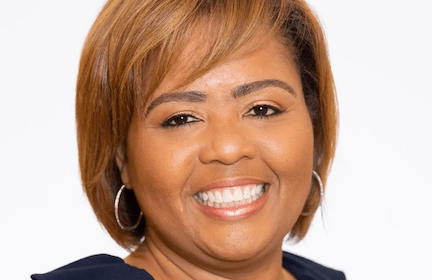 smiling Black woman with short, straight auburn hair and hoop earings in professional headshot